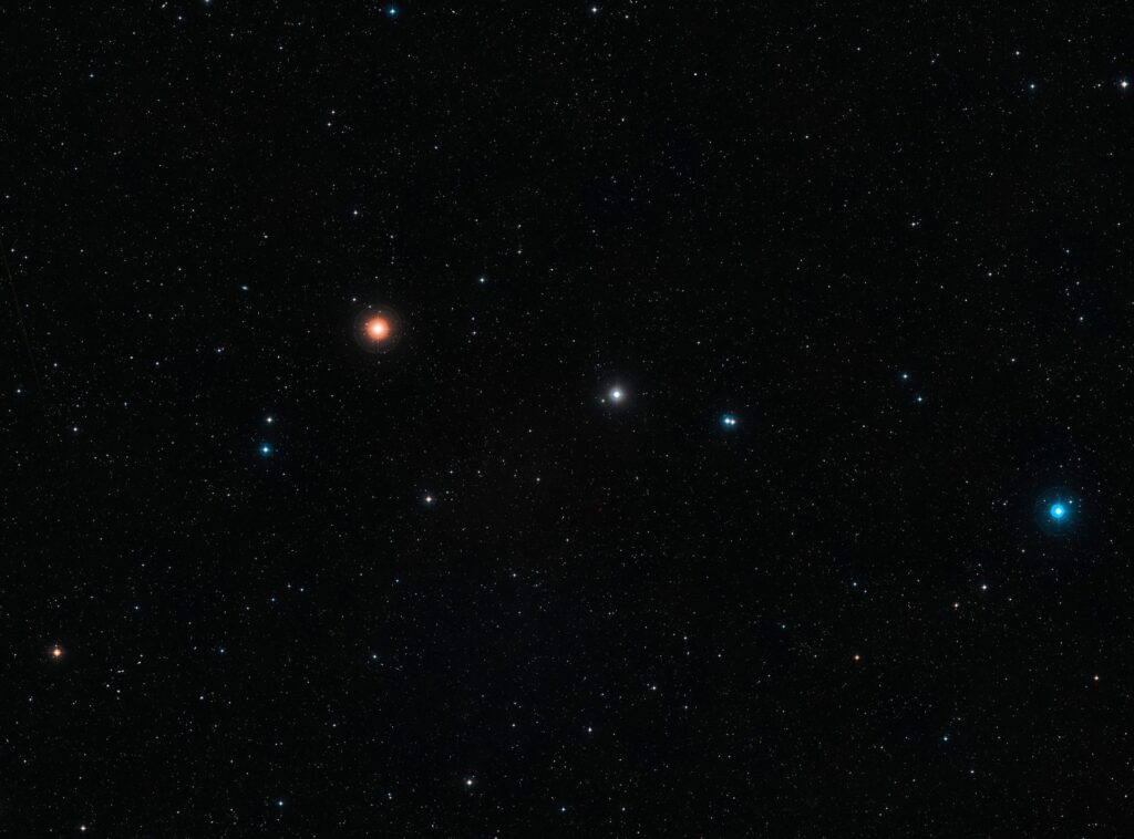 Esta imagen de campo amplio y luz visible del área del cielo donde se encuentra la galaxia remota NGP-190387 fue creada a partir de imágenes del Digital Sky Survey 2. La galaxia, ubicada tan lejos que su luz tardó más de 12 mil millones de años en llegar hasta nosotros, se encuentra cerca del centro de la imagen. Aunque no es visible en esta imagen, se pueden ver muchas otras galaxias mucho más cercanas en esta vista de campo amplio. Crédito: ESO / Digital Sky Survey 2, Reconocimiento: Davide De Martin